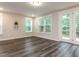 A well lit living room with beautiful floors, large windows, and a glass paneled door leading to a deck at 2008 Van Hook Ln, Apex, NC 27502