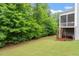 Backyard view with mature trees and lush greenery, complemented by a partially visible deck and screen porch at 213 Preatonwood Dr, Apex, NC 27539