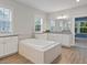 Bright bathroom with white cabinets, granite countertops, a tub, and natural light from two windows at 213 Preatonwood Dr, Apex, NC 27539