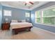 Blue bedroom with natural light from many windows, a ceiling fan, and neutral carpet at 213 Preatonwood Dr, Apex, NC 27539