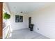 Welcoming outdoor patio with a white wall, black framed window, hanging fern, and potted plants near a dark door at 248 Daniel Ridge Rd, Wendell, NC 27591