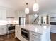 Bright, open kitchen features stainless steel appliances, white cabinetry, large island with pendant lighting, and hardwood floors at 2637 Sidford Aly, Raleigh, NC 27608