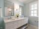 Bright bathroom featuring double vanity with marble countertop, two mirrors, and tiled shower at 2641 Sidford Aly, Raleigh, NC 27608