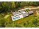 Bird's-eye view of a modern estate with a sleek pool, surrounded by lush greenery and mature trees at 295 Lystra Preserve Dr, Chapel Hill, NC 27517