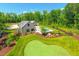 Aerial shot of a modern home featuring a putting green, pool, and manicured lawn in a wooded setting at 295 Lystra Preserve Dr, Chapel Hill, NC 27517