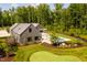 Aerial view of home featuring an in-ground pool, putting green, manicured lawn, and wooded area at 295 Lystra Preserve Dr, Chapel Hill, NC 27517