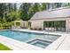 Stunning pool and spa featuring white tiled patio, bar, and lush greenery at 295 Lystra Preserve Dr, Chapel Hill, NC 27517