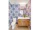 Stylish powder room featuring patterned wallpaper, a round mirror, and floating wood vanity with modern fixtures at 295 Lystra Preserve Dr, Chapel Hill, NC 27517
