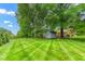Spacious backyard with lush green grass, mature trees, and a shed at 3027 Truitt Dr, Burlington, NC 27215