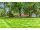 Expansive backyard featuring lush lawn, brick home, mature trees, and storage shed at 3027 Truitt Dr, Burlington, NC 27215