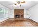 Bright living room featuring a red brick fireplace, built-in shelving, and hardwood floors at 3027 Truitt Dr, Burlington, NC 27215