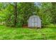 Home's backyard featuring a storage shed nestled among mature trees at 3027 Truitt Dr, Burlington, NC 27215