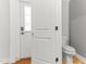 Bathroom with white door ajar, toilet, and hardwood floors; natural light coming through door window at 305 Georgetown Rd, Raleigh, NC 27608