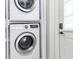 Laundry room featuring white stacked washer and dryer set; door with handle at 305 Georgetown Rd, Raleigh, NC 27608