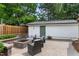 Backyard patio with a built-in stone fire pit, outdoor seating, string lights, and detached garage at 305 Georgetown Rd, Raleigh, NC 27608