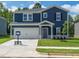 Charming two-story blue home featuring a well-manicured lawn, attached garage, and inviting front entrance at 3861 Rosebush Dr, Zebulon, NC 27597