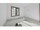 Well-lit bedroom with large window showing tree view, freshly painted white walls and unfinished floors at 5013 Coronado, Raleigh, NC 27609