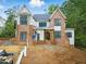 New two-story home featuring a brick facade, light gray siding and black-framed windows surrounded by a landscaped yard at 5013 Coronado, Raleigh, NC 27609