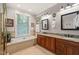 Well-lit bathroom with double sink vanity, granite countertops, and a large soaking tub at 5405 Bluet Ct, Holly Springs, NC 27540