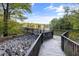 Peaceful view of a serene lake with a wooden walking bridge surrounded by lush trees and greenery at 5405 Bluet Ct, Holly Springs, NC 27540