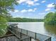 Scenic lake view with a black metal walking bridge and lush green trees in the background at 5405 Bluet Ct, Holly Springs, NC 27540