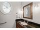 Elegant powder room with granite countertop, decorative mirror, sconces, and unique oval window at 5405 Bluet Ct, Holly Springs, NC 27540