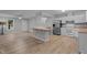 Open-concept kitchen with white cabinets, breakfast bar, stainless steel refrigerator, and wood-look floors at 627 Gaslight Trl, Wendell, NC 27591