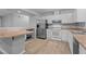 Well-lit kitchen with white cabinets, stainless steel refrigerator, and breakfast bar offering views into the adjoining rooms at 627 Gaslight Trl, Wendell, NC 27591