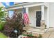 Inviting front porch with an American flag, decorative wreath, and colorful flowerbeds creating a warm welcome at 66 Arlie Ln, Lillington, NC 27546