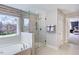 Bright bathroom featuring a soaking tub, glass-enclosed shower, and large window at 673 Sun Meadow Dr, Wake Forest, NC 27587