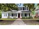 Charming two-story home with classic black shutters, a vibrant red front door, and lush landscaping at 830 S Chestnut St, Henderson, NC 27536