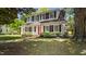 Quaint two-story white home featuring black shutters and a vibrant red front door at 830 S Chestnut St, Henderson, NC 27536