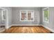 Bright living room with gleaming hardwood floors and large windows offering plenty of natural light at 830 S Chestnut St, Henderson, NC 27536
