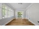 Sunlit room with plank flooring, surrounded by windows and double doors to outside at 830 S Chestnut St, Henderson, NC 27536