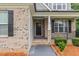 Close up of a brick home's front porch with black door, railing and manicured flower beds at 90 Starwood Dr, Garner, NC 27529