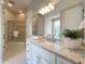Updated bathroom with white cabinets, granite countertops, decorative lighting, and tiled shower at 1000 Clovelly Ct, Raleigh, NC 27614