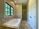 Bright bathroom featuring a luxurious soaking tub, tiled shower, and a window, offering a relaxing spa-like experience at 1000 Clovelly Ct, Raleigh, NC 27614