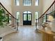 Grand foyer with tiled floor, staircase, and transom windows over a black front door at 1000 Clovelly Ct, Raleigh, NC 27614