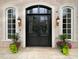 Elegant brick home entrance featuring a black double door, arched windows, and decorative planters at 1000 Clovelly Ct, Raleigh, NC 27614