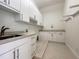 Functional laundry room with white cabinetry, tile flooring, countertop workspace, and utility sink at 1000 Clovelly Ct, Raleigh, NC 27614