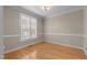 Bright bedroom featuring hardwood floors, white trim, and plantation shutters at 1012 Coram Fields Rd, Wake Forest, NC 27587