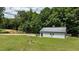 Outbuilding view featuring a white exterior, dark roof, and quaint details amidst a spacious green yard at 102 Ridge Ln, Youngsville, NC 27596