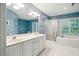 Bright bathroom featuring a double sink vanity, soaking tub, and a glass shower with blue walls at 103 Red Cedar Pl, Chapel Hill, NC 27514
