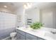 Bright bathroom features a double sink vanity with gray cabinets, and shower with decorative curtain at 1048 Flagler St, Durham, NC 27713