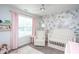 Charming Bedroom with floral wallpaper, white crib, comfortable chair, and soft pink accents at 1048 Flagler St, Durham, NC 27713