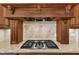 Close up of the cooktop with custom wood hood, stone tile backsplash, and granite countertops at 105 Somerley Dr, Garner, NC 27529