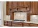 The kitchen has granite countertops, stone tile backsplash, and stainless gas cooktop with custom wood hood at 105 Somerley Dr, Garner, NC 27529