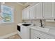 Laundry room with white cabinets, sink, countertop, and window letting in natural light at 105 Somerley Dr, Garner, NC 27529