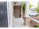 Covered front porch featuring decorative stone accents, a stylish light fixture, and views of the landscaped yard at 110 Elmsford St, Durham, NC 27707
