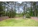 Secluded backyard with a playground, tall trees, and a wooden fence, providing a safe and natural play area at 1211 Whispering Oak Ln, Durham, NC 27704